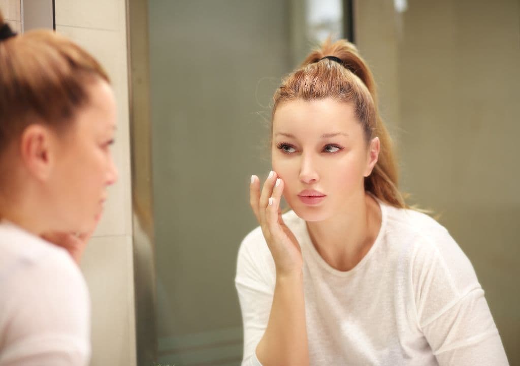 A woman is touching her face to see if her skin is good. And it is.