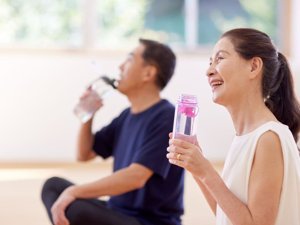 A couple sitting down and drinking water